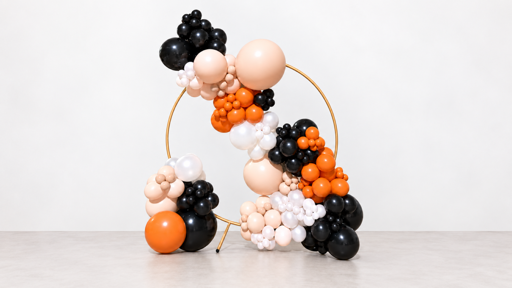 Pop Up Pretty balloon arrangement with orange, black and light balloons on a gold frame